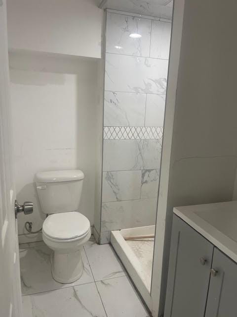 bathroom with vanity, toilet, marble finish floor, and a stall shower