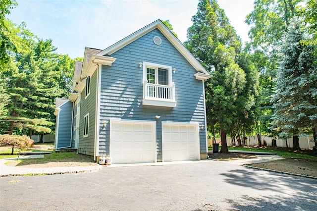 view of side of property with a garage, driveway, and fence