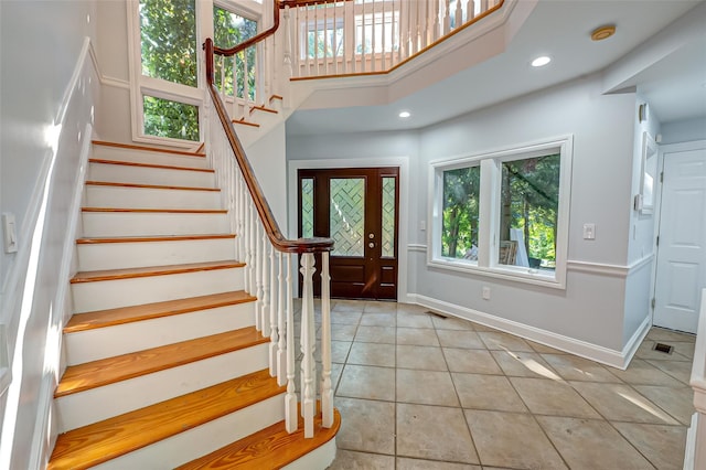 foyer featuring light tile patterned floors, baseboards, visible vents, a high ceiling, and recessed lighting