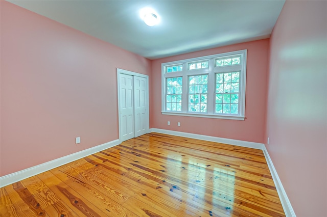 unfurnished bedroom featuring light wood finished floors, a closet, and baseboards