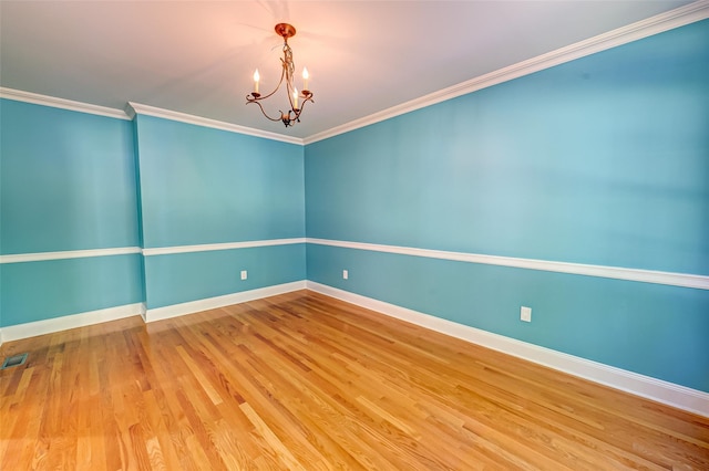 unfurnished room with baseboards, visible vents, wood finished floors, crown molding, and a chandelier