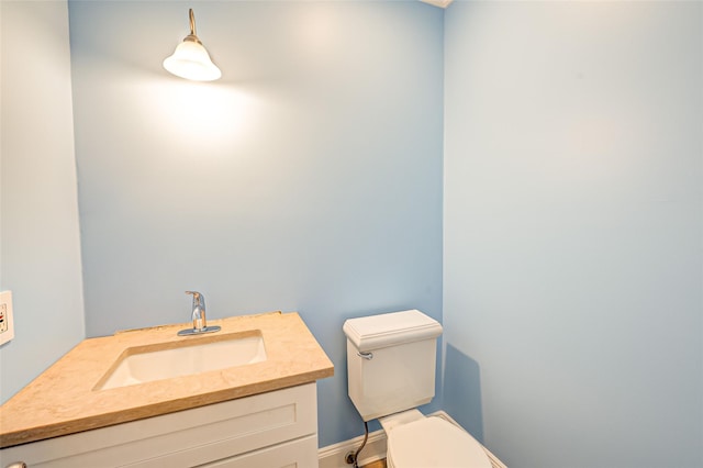 half bathroom featuring baseboards, vanity, and toilet