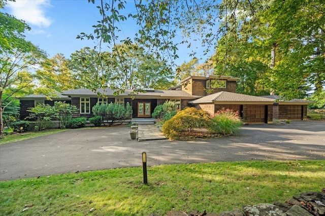 view of front of house featuring a garage, french doors, and aphalt driveway