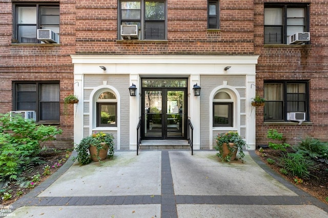 view of exterior entry featuring cooling unit, french doors, and brick siding