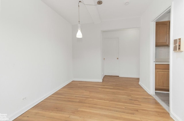 unfurnished dining area featuring vaulted ceiling, light wood-style flooring, and baseboards