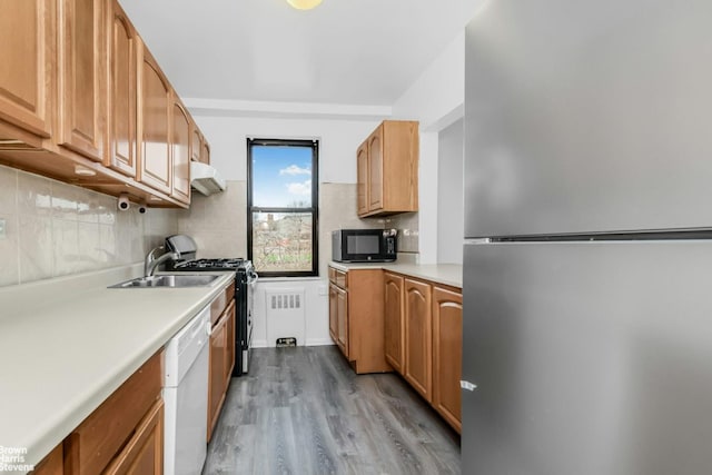 kitchen featuring freestanding refrigerator, gas range oven, white dishwasher, black microwave, and a sink