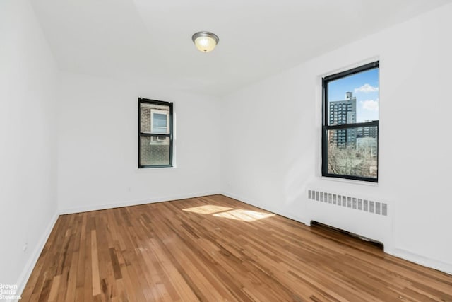 spare room featuring radiator, baseboards, and wood finished floors