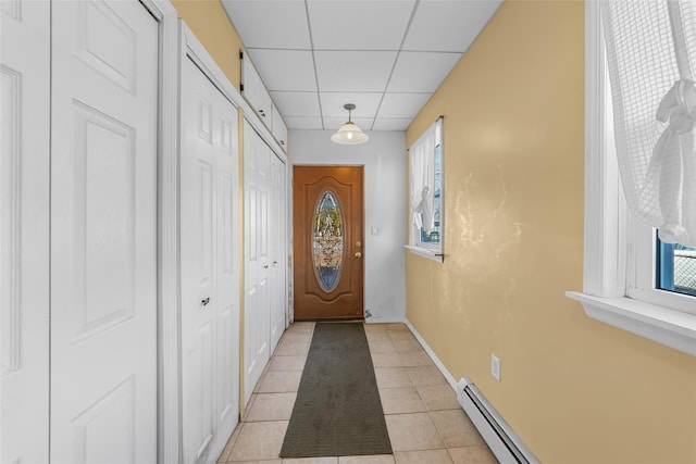 entryway featuring a paneled ceiling, light tile patterned floors, baseboards, and a wealth of natural light