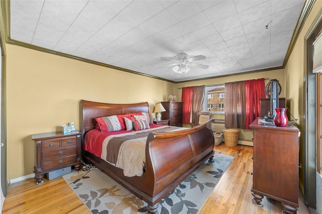 bedroom featuring crown molding, baseboard heating, and wood finished floors