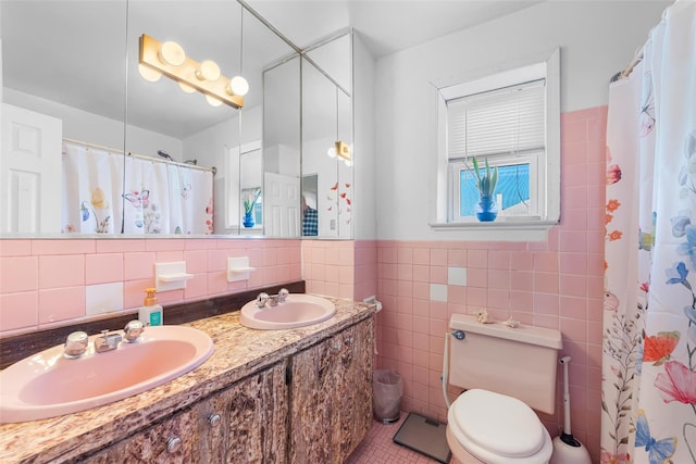 full bath with a sink, tile walls, toilet, and double vanity