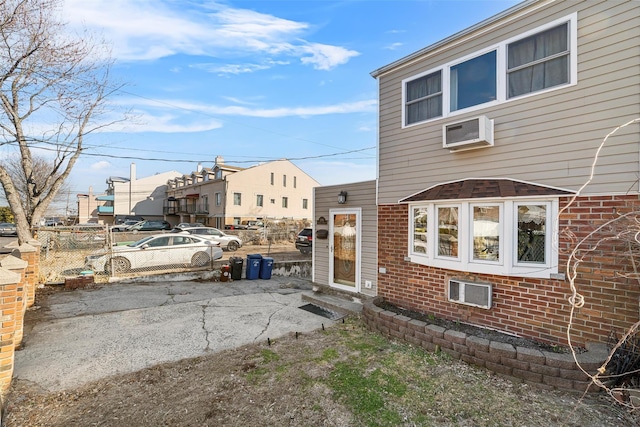 exterior space featuring fence, an AC wall unit, and brick siding