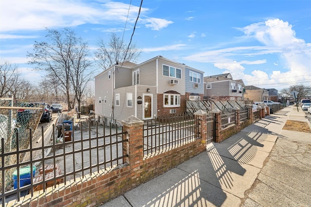 view of front facade featuring concrete driveway, a fenced front yard, a gate, and a residential view