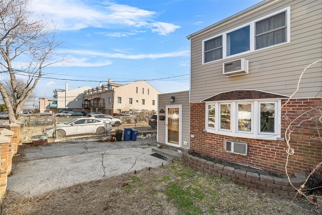 3296 Griswold Ave, Bronx, NY 10465 - view of side of home featuring brick siding, fence, entry steps, and a wall mounted air conditioner