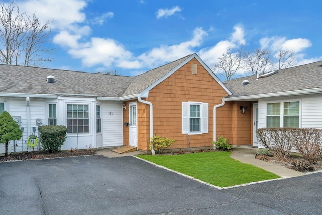 view of front facade with a shingled roof and a front lawn