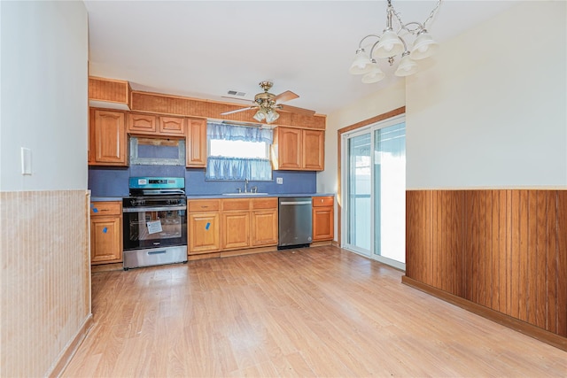 kitchen with visible vents, a wainscoted wall, light wood-type flooring, appliances with stainless steel finishes, and a sink