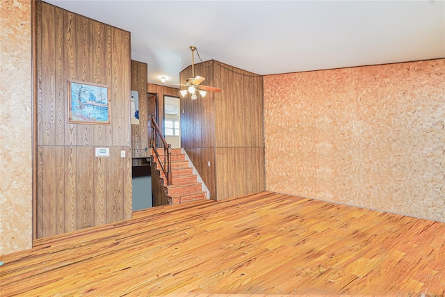 spare room featuring stairs, wood-type flooring, and ceiling fan