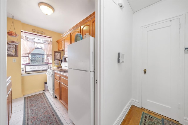 kitchen featuring light tile patterned floors, baseboards, white appliances, and light countertops