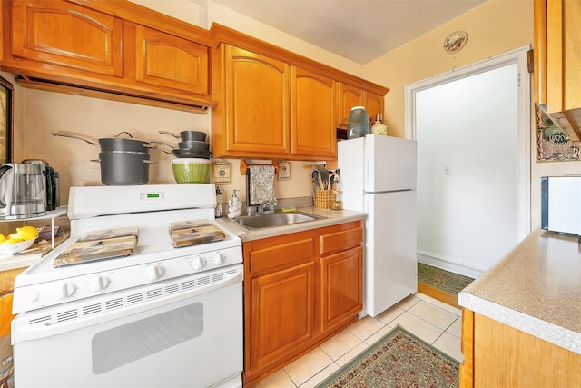 kitchen with white appliances, light tile patterned floors, a sink, light countertops, and brown cabinets