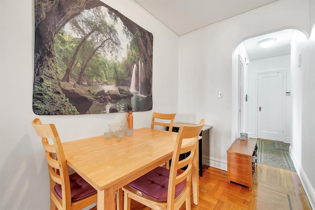 dining space with baseboards and arched walkways