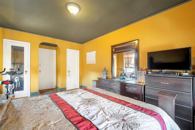 bedroom featuring baseboards and arched walkways