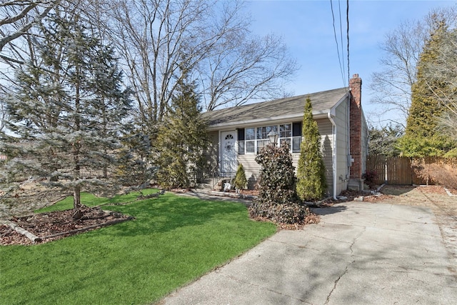 view of front of home with fence, a chimney, and a front lawn