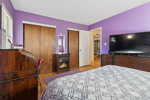 bedroom with a lit fireplace and wood finished floors