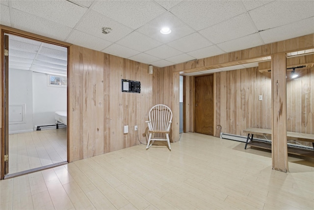 unfurnished room featuring a drop ceiling, wooden walls, and wood finished floors