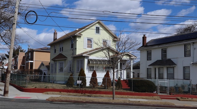 view of front of property featuring a chimney, a residential view, and a fenced front yard