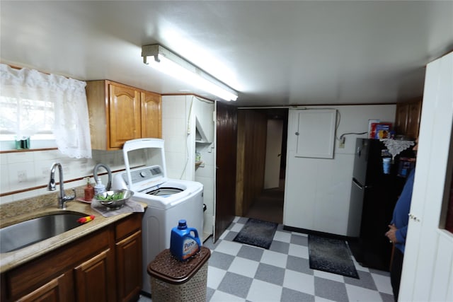 clothes washing area featuring washer / dryer, laundry area, electric panel, dark floors, and a sink