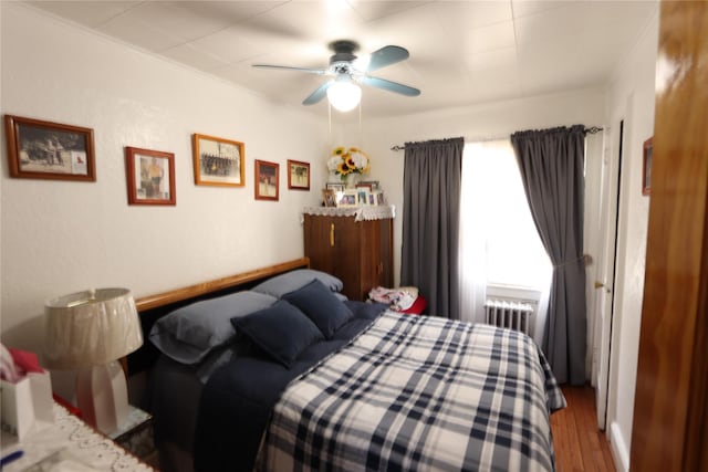 bedroom with radiator, ceiling fan, and wood finished floors