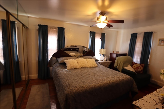 bedroom with ceiling fan, wood finished floors, and baseboards