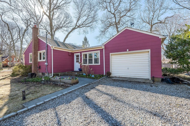 view of front of house with a chimney, gravel driveway, and an attached garage