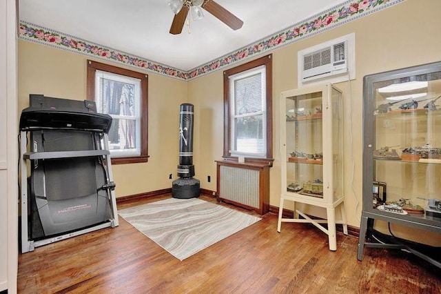 workout area with radiator heating unit, a wealth of natural light, and wood finished floors