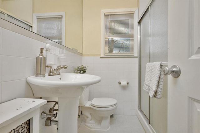 bathroom featuring tile patterned flooring, a shower stall, toilet, and tile walls