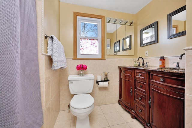 bathroom featuring tile patterned flooring, wainscoting, tile walls, and toilet