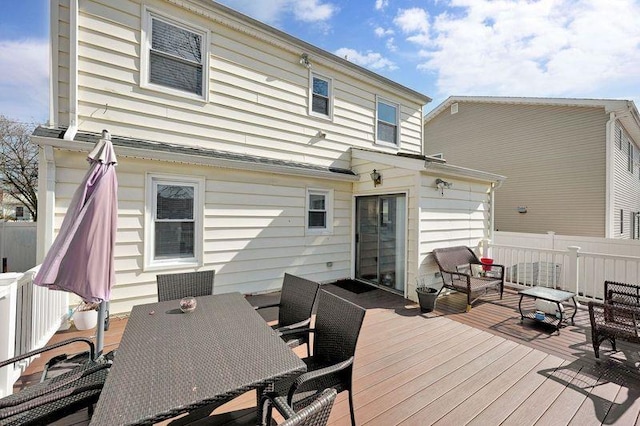 rear view of house featuring outdoor dining space, fence, and a deck