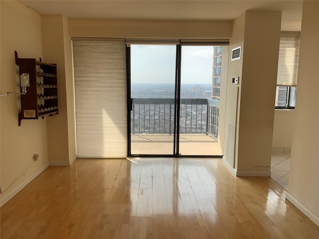 spare room featuring light wood-style flooring, visible vents, and baseboards