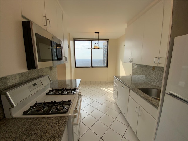 kitchen with light tile patterned floors, white appliances, a sink, white cabinetry, and tasteful backsplash