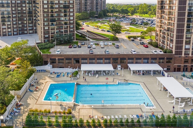 community pool featuring a patio, fence, and a city view