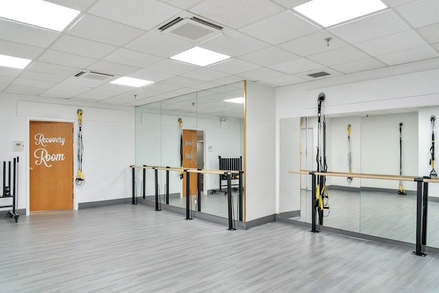 interior space with baseboards, visible vents, a drop ceiling, and wood finished floors