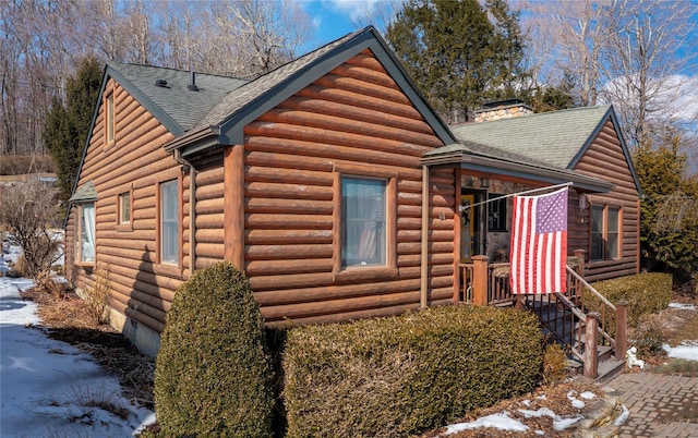 view of side of home featuring a chimney and a shingled roof