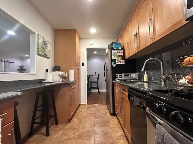 kitchen with stainless steel appliances, brown cabinetry, a sink, and tasteful backsplash