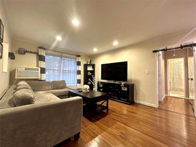 living room with baseboards, ornamental molding, wood finished floors, a wall mounted AC, and recessed lighting