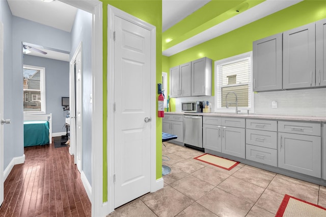 kitchen with appliances with stainless steel finishes, a wealth of natural light, and gray cabinets