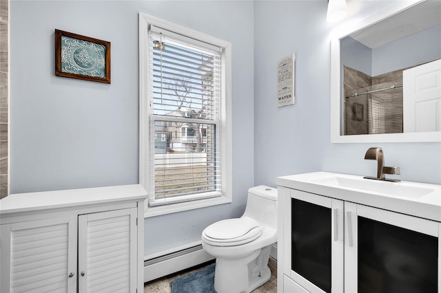 bathroom featuring a baseboard radiator, tiled shower, vanity, and toilet