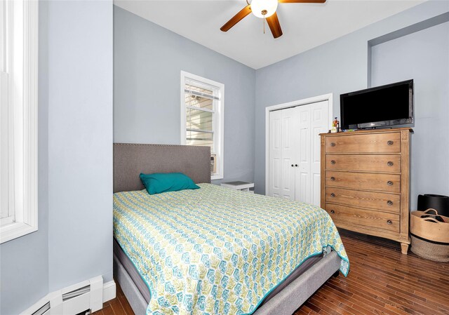 bedroom with ceiling fan, a closet, baseboard heating, and wood finished floors