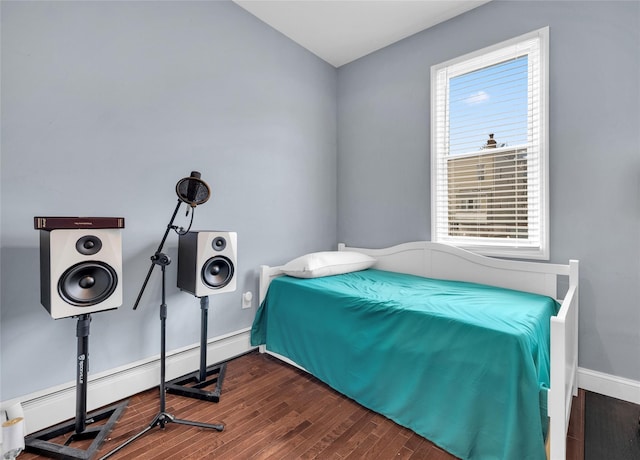 bedroom featuring baseboard heating, wood finished floors, and baseboards