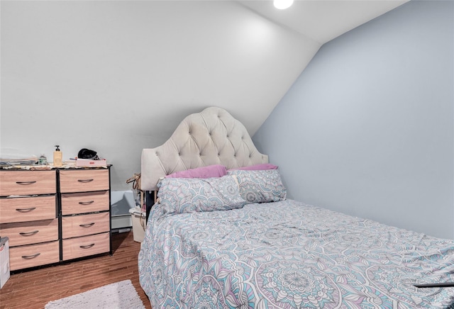 bedroom featuring a baseboard heating unit, lofted ceiling, and wood finished floors