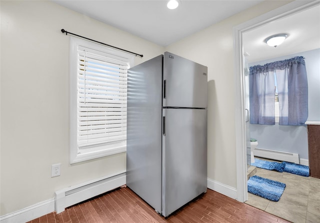 kitchen with baseboard heating, a baseboard heating unit, freestanding refrigerator, wood finished floors, and baseboards