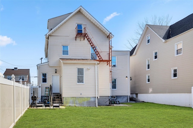 rear view of house featuring entry steps, a yard, and fence